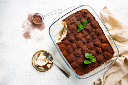 Traditional Italian dessert tiramisu in a glass backing form on light background, top view