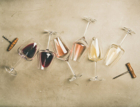 Witte, rode en rosé wijn in glazen liggend met kurkentrekkers